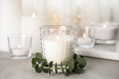 Burning aromatic candle and eucalyptus branch on table