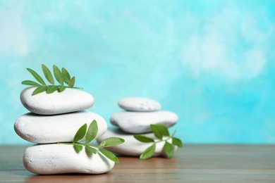 Spa stones and bamboo leaves on table against color background. Space for text