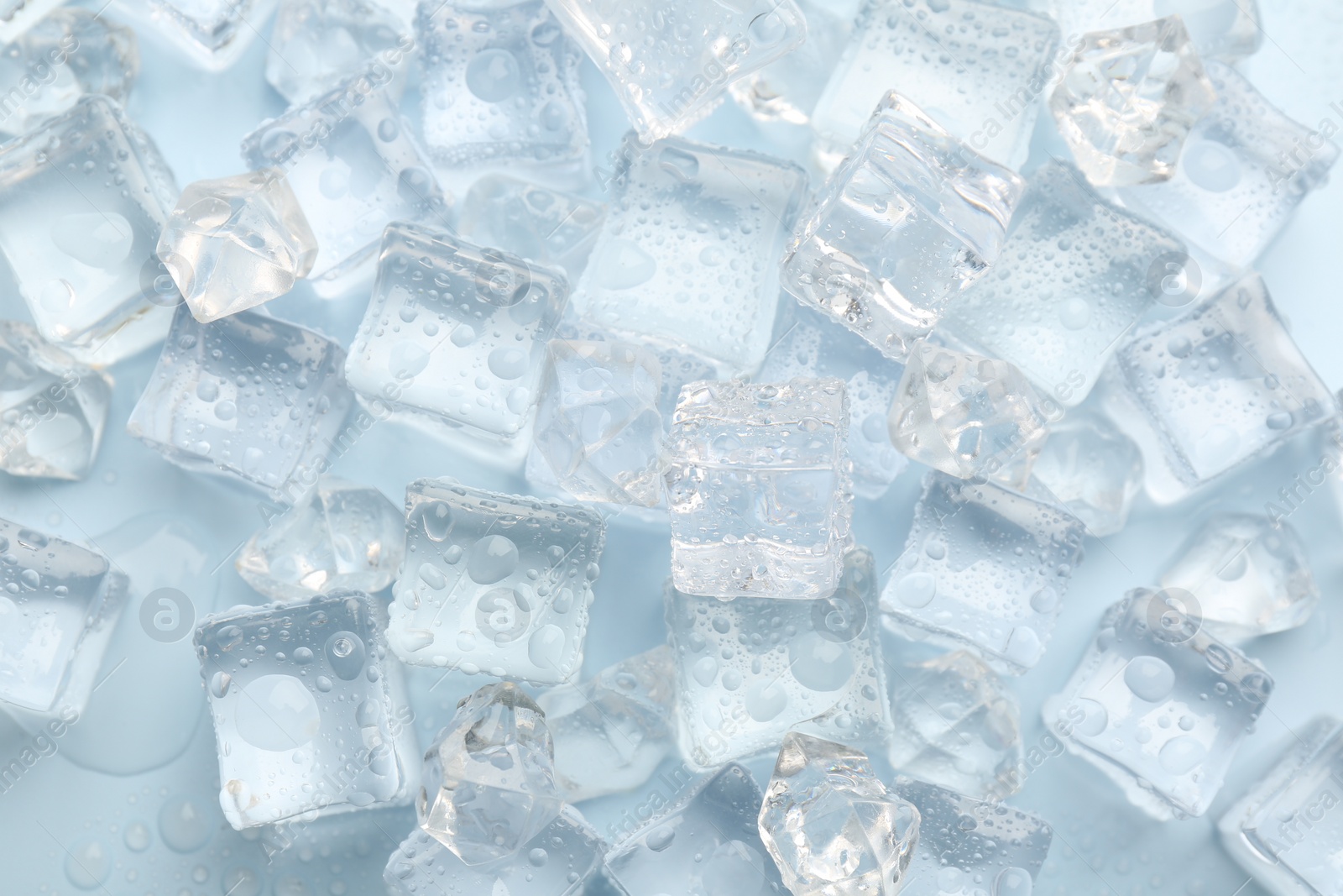 Photo of Crystal clear ice cubes on light blue background, flat lay