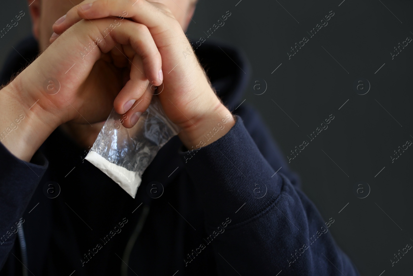 Photo of Criminal holding plastic bag with drug indoors, space for text