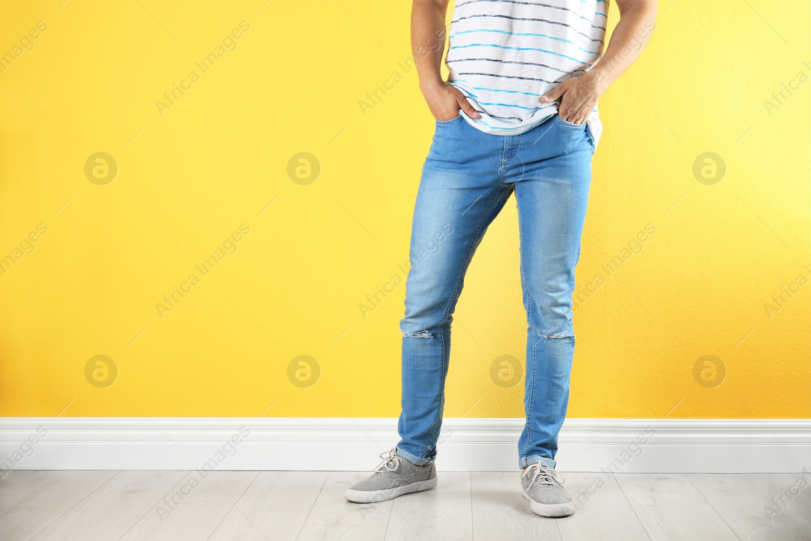 Photo of Young man in stylish jeans near color wall