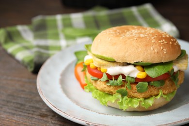 Photo of Tasty vegan burger with vegetables, patty and microgreens on wooden table, closeup. Space for text