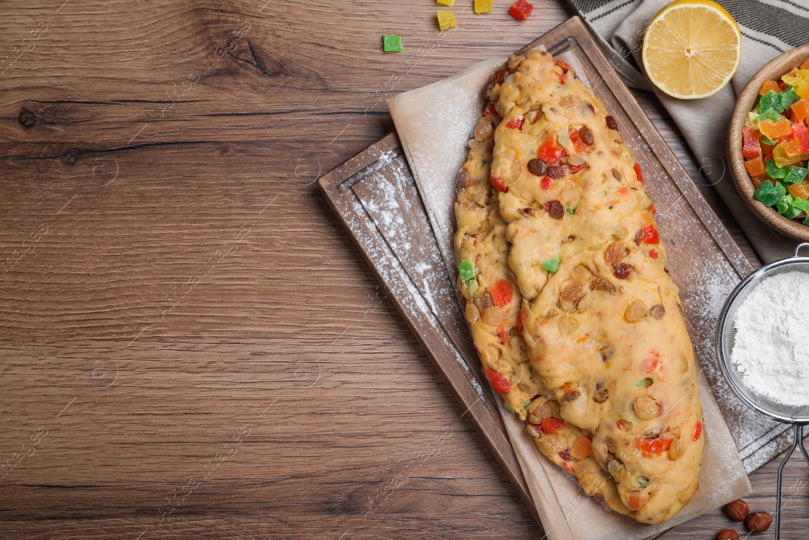 Photo of Unbaked Stollen with candied fruits and raisins on wooden table, flat lay. Space for text