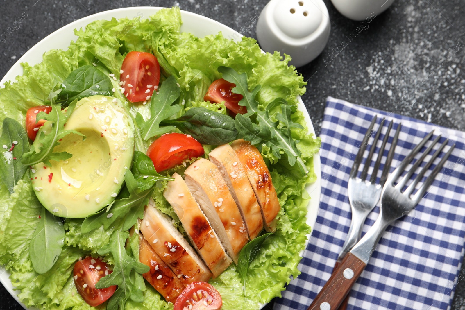 Photo of Delicious salad with chicken, cherry tomato and avocado served on grey textured table, top view