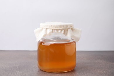 Homemade fermented kombucha in glass jar on grey table
