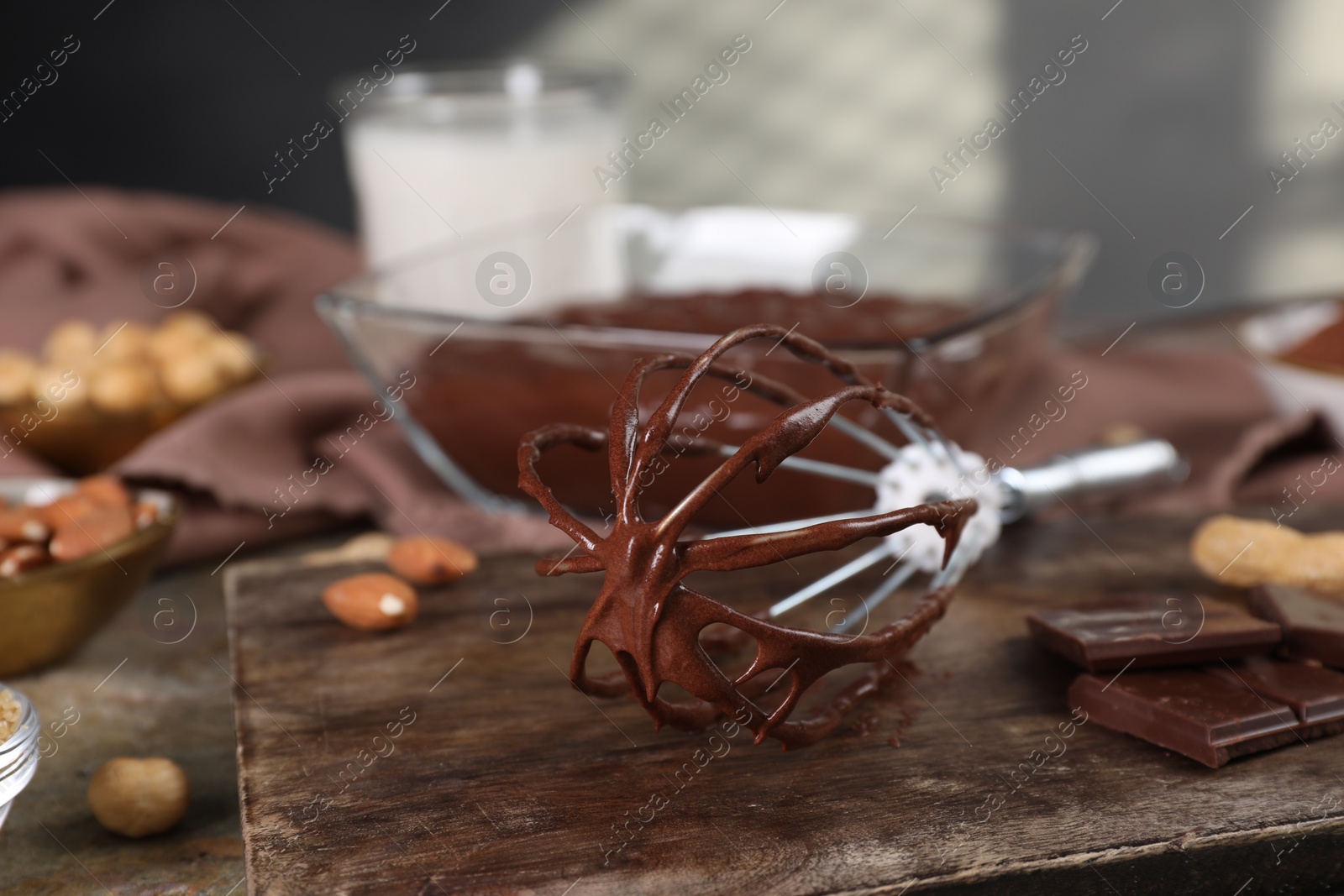 Photo of Whisk with chocolate cream on table, closeup. Space for text