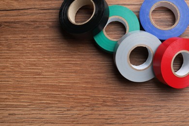 Photo of Colorful insulating tapes on wooden table, flat lay. Space for text