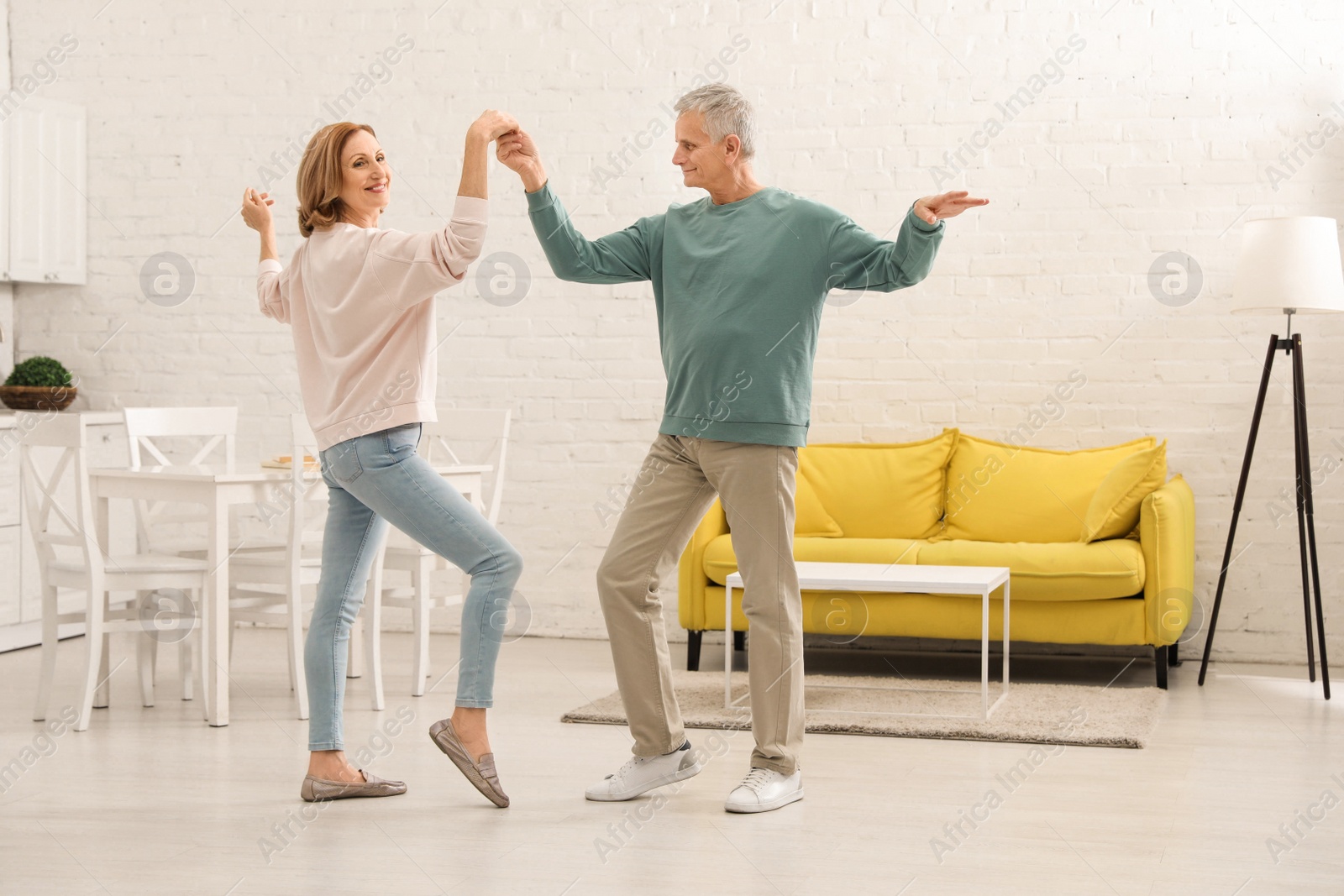 Photo of Happy senior couple dancing together in kitchen