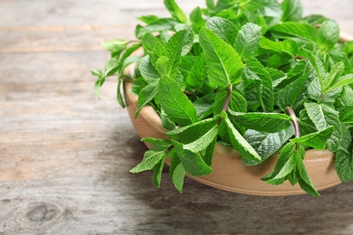 Photo of Bowl with fresh mint on wooden table