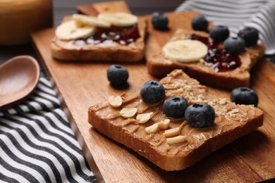 Different tasty toasts with nut butter and products on table, closeup
