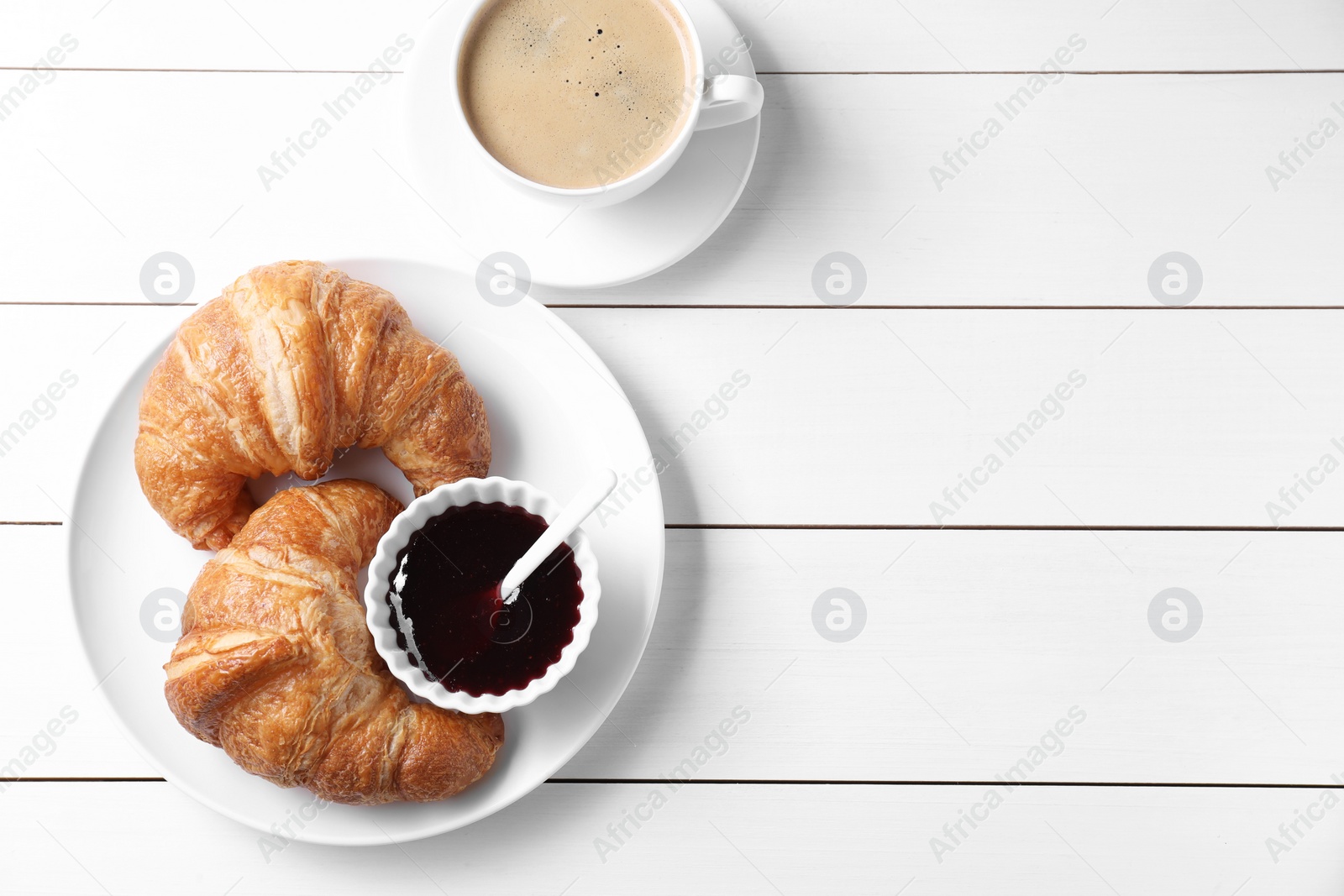 Photo of Breakfast time. Fresh croissants, jam and coffee on white wooden table, flat lay. Space for text