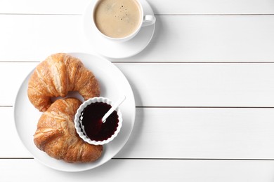 Breakfast time. Fresh croissants, jam and coffee on white wooden table, flat lay. Space for text