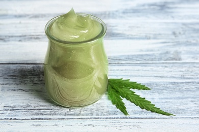 Jar with hemp lotion on wooden background