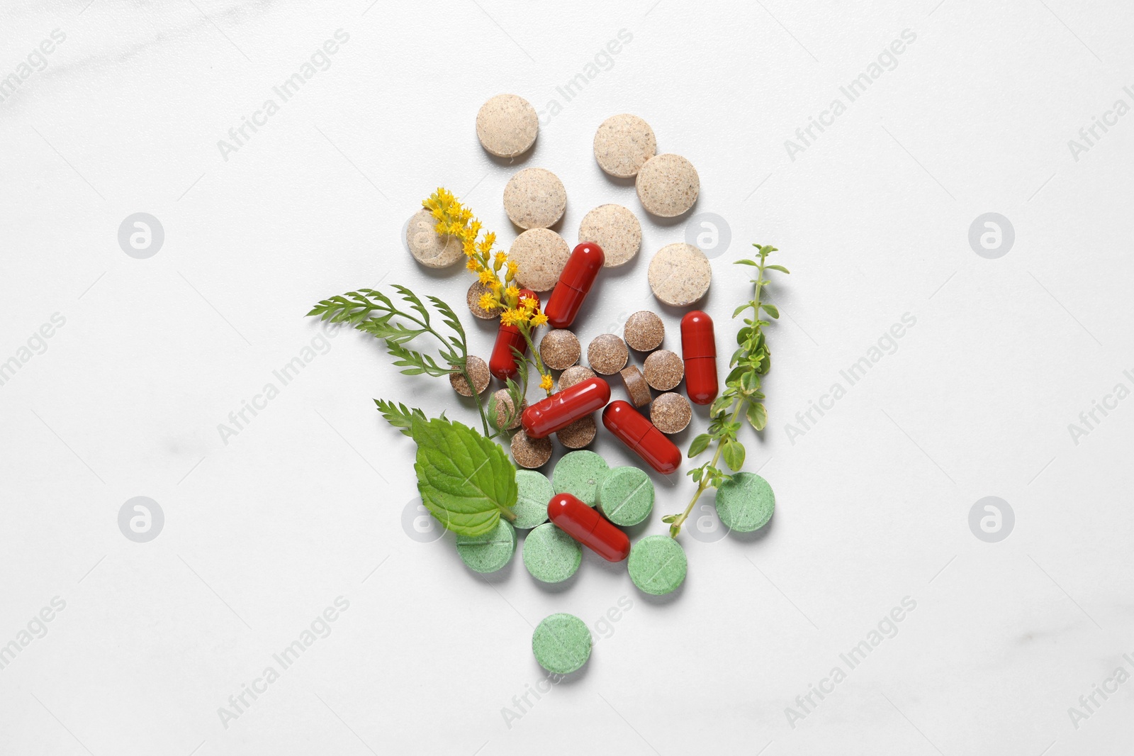 Photo of Different pills and herbs on white table, flat lay. Dietary supplements