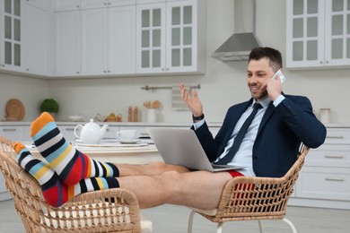 Businessman in shirt and underwear talking on phone during video call at home