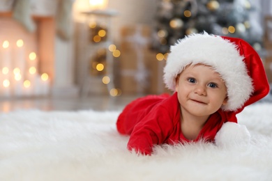 Photo of Little baby wearing Santa hat on floor at home. First Christmas