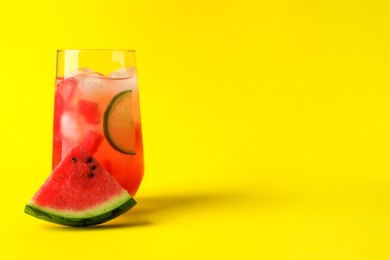 Photo of Tasty summer watermelon drink with lime in glass on yellow background. Space for text