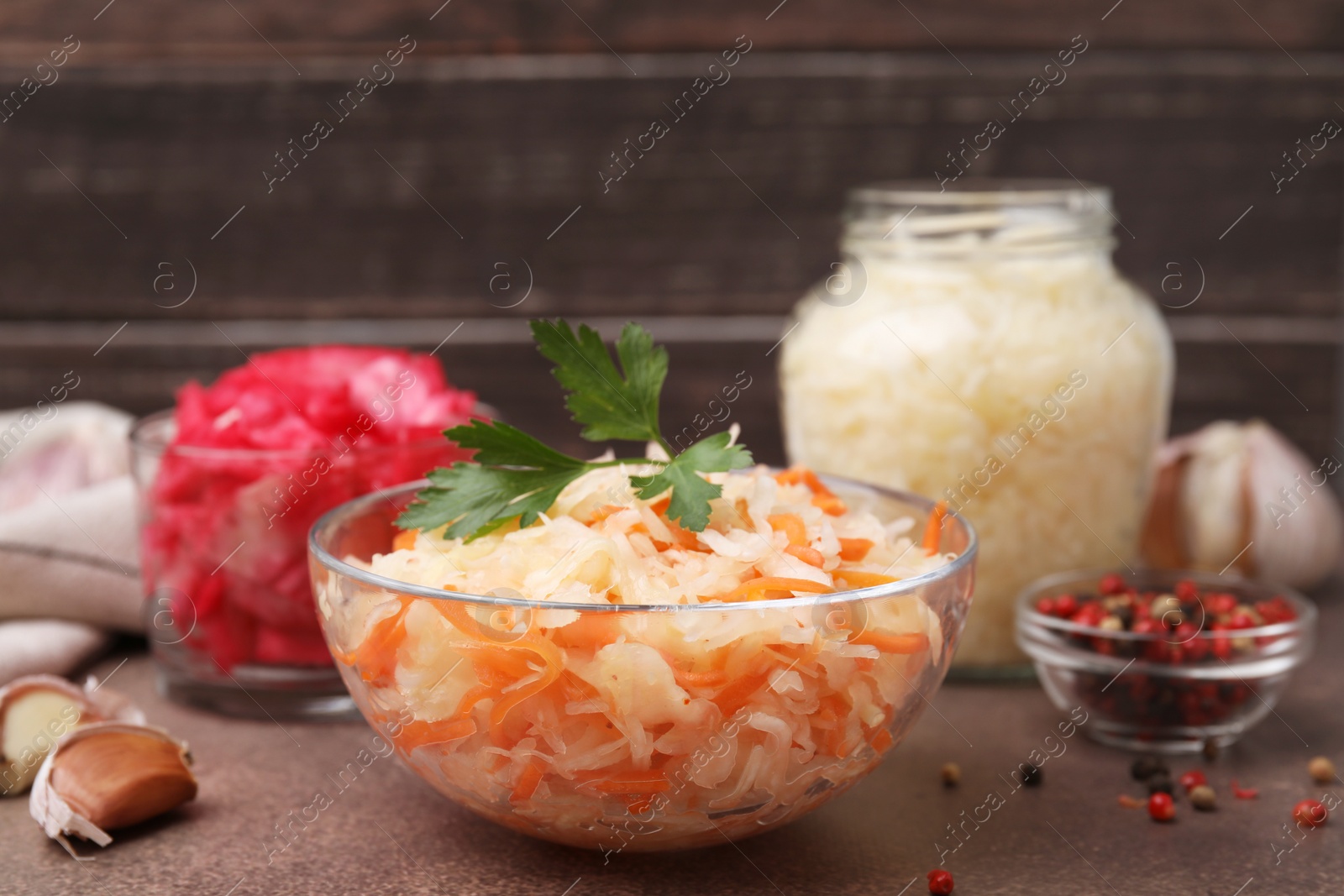 Photo of Delicious sauerkraut prepared according to different recipes on brown table, closeup view