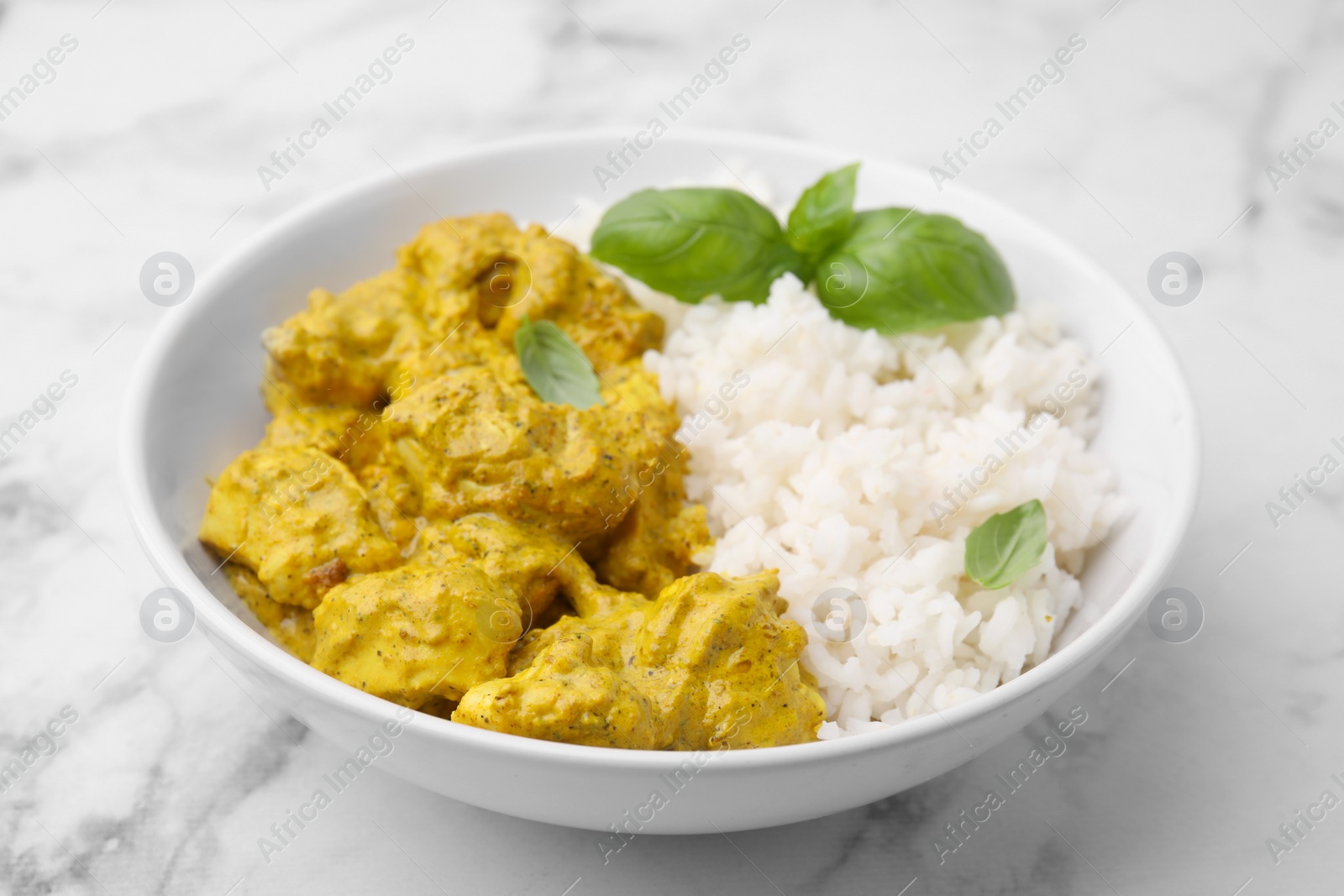 Photo of Delicious rice and chicken with curry sauce on white marble table, closeup