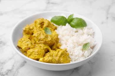 Photo of Delicious rice and chicken with curry sauce on white marble table, closeup