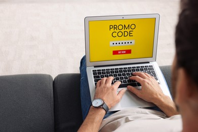 Photo of Man holding laptop with activated promo code on sofa, closeup