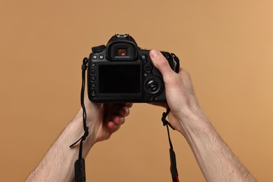 Photographer holding camera on beige background, closeup