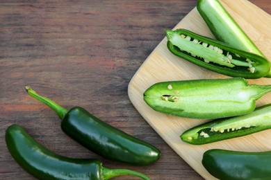 Photo of Fresh green jalapeno peppers on wooden table, flat lay. Space for text