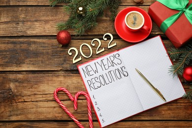 Making resolutions for 2022 New Year. Flat lay composition with notebook and festive decor on wooden table