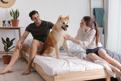 Couple and Akita Inu dog in bedroom decorated with houseplants