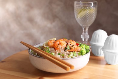 Tasty rice with shrimps and vegetables served on wooden table