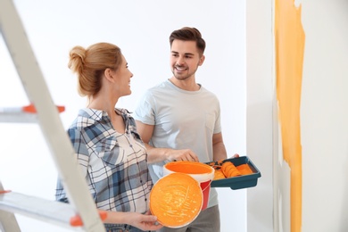 Photo of Happy couple painting wall indoors. Home repair