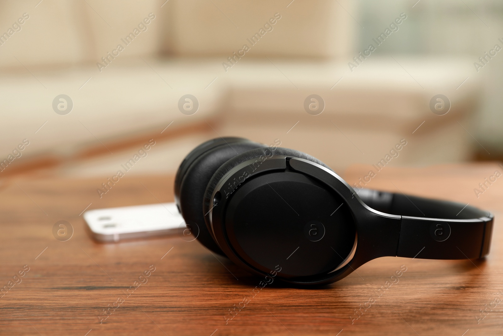 Photo of Modern wireless headphones and smartphone on wooden table indoors