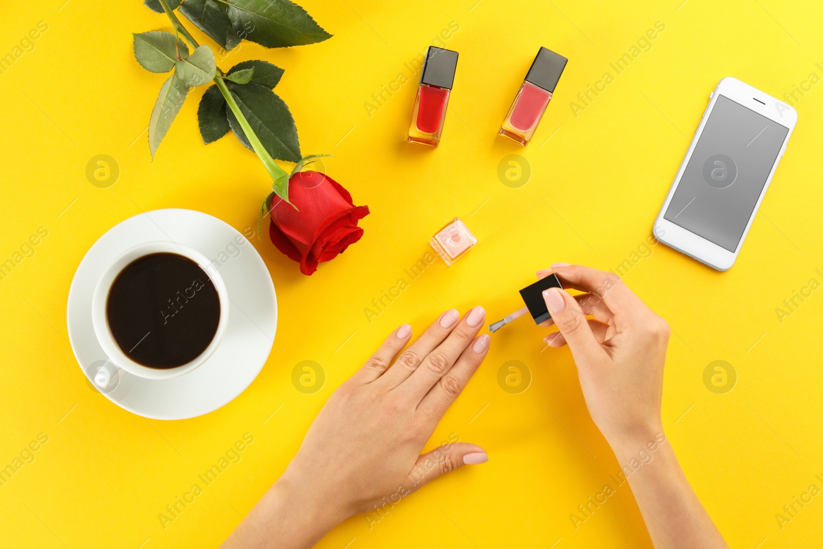 Photo of Woman applying nail polish on color background, top view