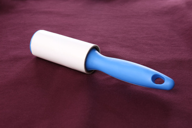 Photo of New lint roller with blue handle on red fabric