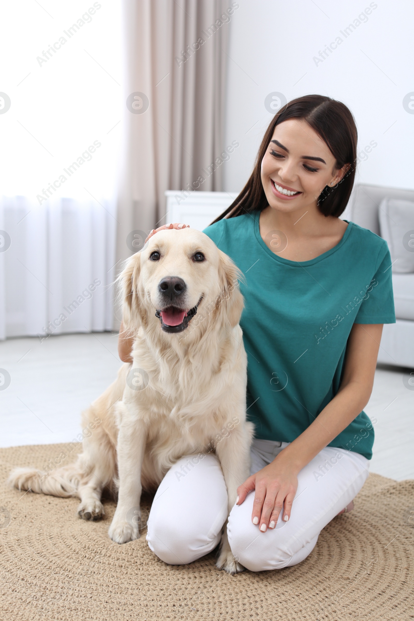 Photo of Young woman and her Golden Retriever dog in living room