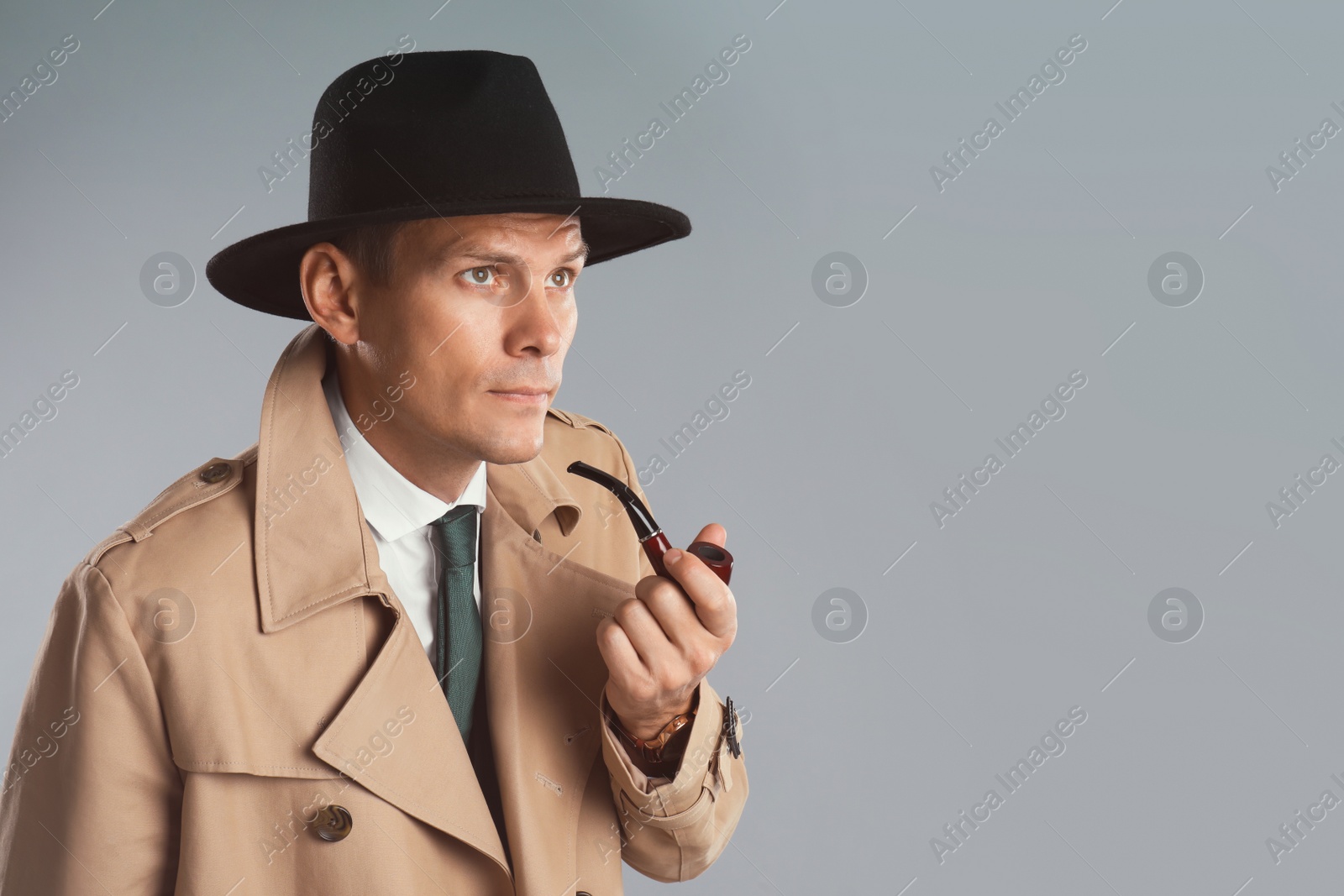 Photo of Male detective with smoking pipe on grey background. Space for text