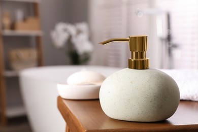 Dispenser with liquid soap on wooden table in bathroom, space for text