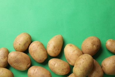 Photo of Fresh raw potatoes on green background, flat lay. Space for text