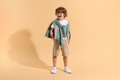 Photo of Fashion concept. Stylish boy on pale orange background