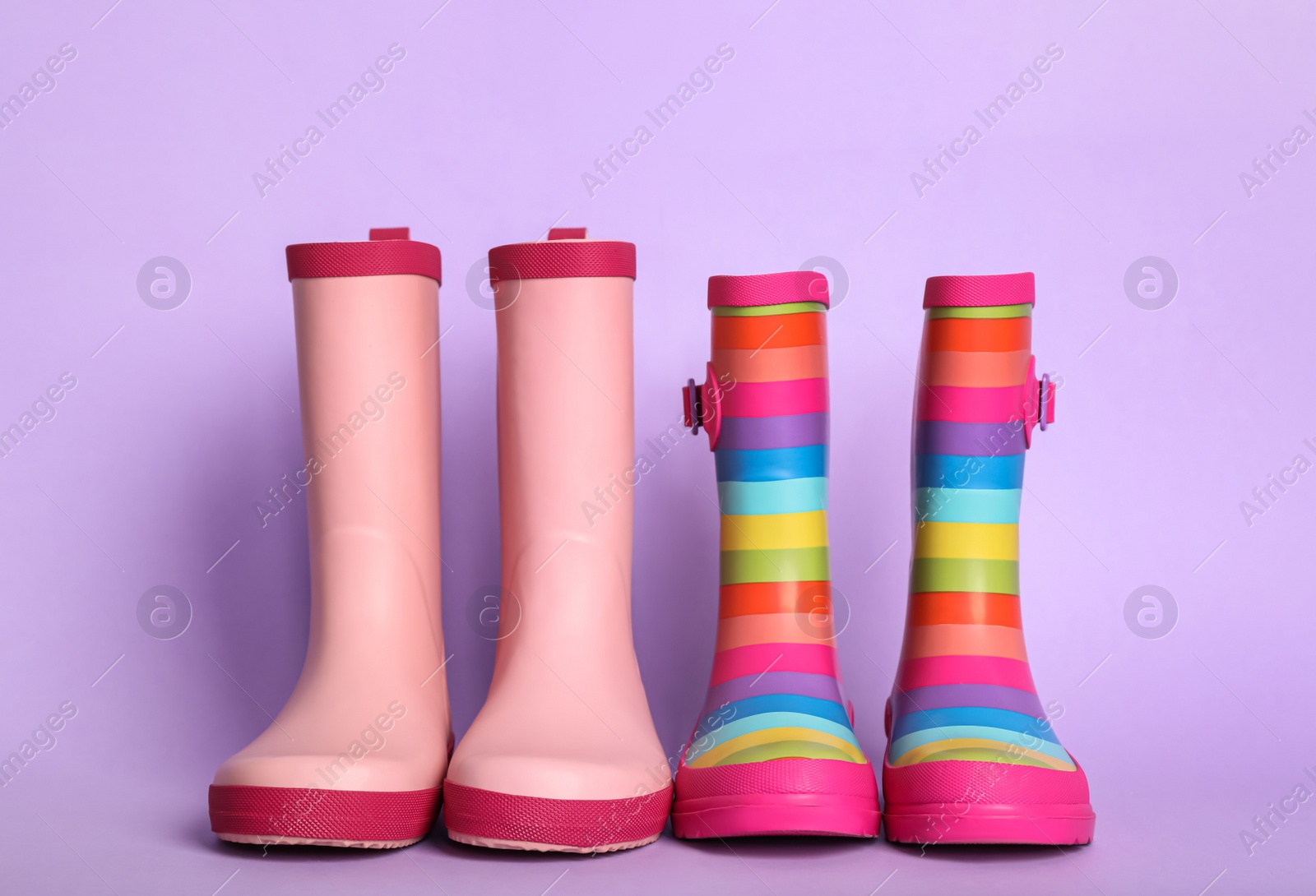 Photo of Two pairs of rubber boots on violet background