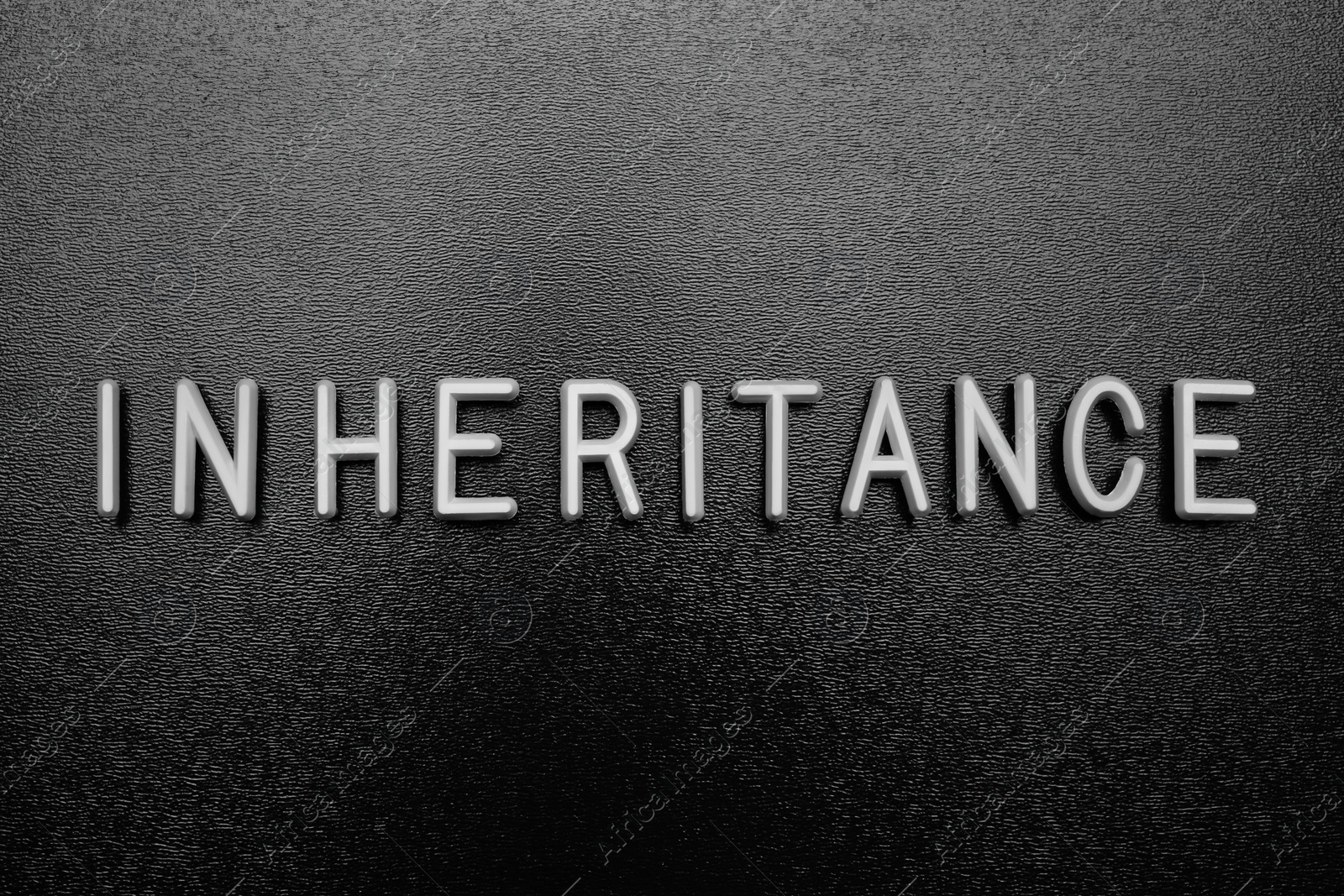 Photo of Word Inheritance made with white letters on black background, flat lay