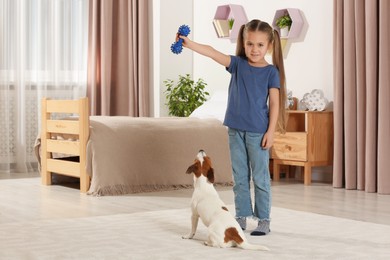 Photo of Cute girl playing with her dog in bedroom at home. Adorable pet