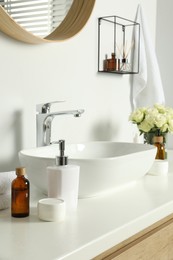 Photo of Bath accessories, sink and roses in bathroom