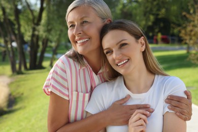 Photo of Family portrait of happy mother and daughter hugging in park
