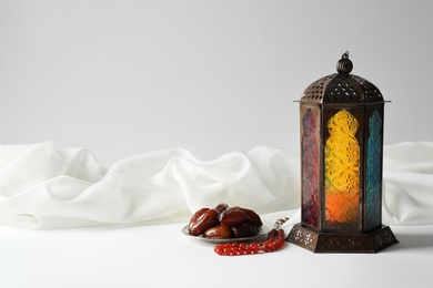 Photo of Muslim lamp, dates and misbaha on light background. Fanous as Ramadan symbol