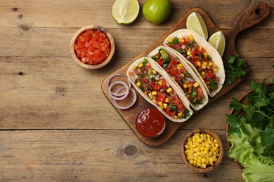 Photo of Tasty tacos with vegetables on wooden table, flat lay. Space for text