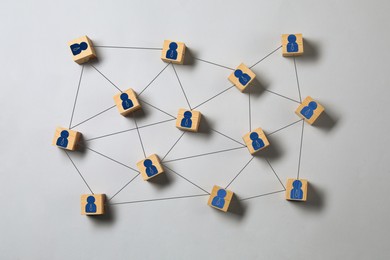 Image of Teamwork. Wooden cubes with human icons linked together symbolizing cooperation on grey background, top view