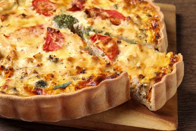 Photo of Tasty quiche with tomatoes and cheese on wooden table, closeup