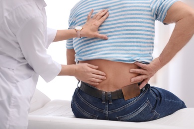 Chiropractor examining patient with back pain in clinic, closeup