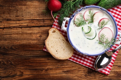 Delicious cold summer soup on wooden table, flat lay. Space for text